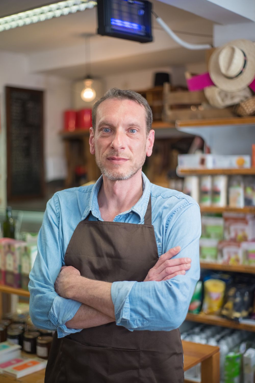 Shop owner standing in his store with arms crossed